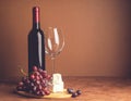 A bottle of wine an empty glass bunch of red grapes a slice of cheese on a dark background. Copy space. Selective focus. Royalty Free Stock Photo