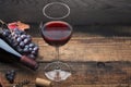 A bottle of wine, a glass, a bunch of grapes and grape leaves on an old wooden table Royalty Free Stock Photo