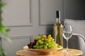 Bottle of wine, glass and fresh grapes on wooden table indoors Royalty Free Stock Photo