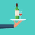 Bottle of wine with glass on tray. Tray in the waiter\'s hand