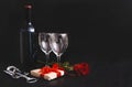 Bottle of wine, 2 glasses, dark grapes, corkscrew, red rose, gift box with ribbon on black background Royalty Free Stock Photo