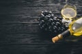 A bottle of wine with glasses and grapes on a black wooden background. Free space for text. Royalty Free Stock Photo