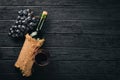 A bottle of wine with glasses and grapes on a black wooden background. Royalty Free Stock Photo