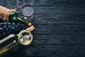 A bottle of wine with glasses and grapes on a black wooden background. Free space for text. Royalty Free Stock Photo