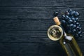 A bottle of wine with glasses and grapes on a black wooden background. Free space for text. Royalty Free Stock Photo