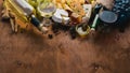 A bottle of wine, and a large assortment of cheeses, honey, nuts and spices, on a wooden table. Top view.