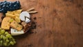 A bottle of wine, and a large assortment of cheeses, honey, nuts and spices, on a wooden table. Top view.