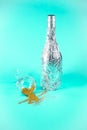 Bottle wrapped in aluminium foil and champagne glass with spilled golden glitter