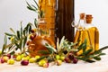 Bottled olive oil and branches with leaves and olives