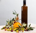 Bottled olive oil and branches with leaves and olives