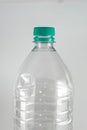 Bottleneck of a empty bottle of a liter and a half of mineral water with sea green cap and sealing ring on a white