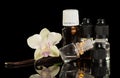 Bottles of aromatic liquid for vaping, vanilla pods and Orchid flower isolated on black