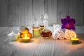 Bottles of aromatic oils with candles, pink orchid, stones and white towel on vintage wooden background with vignette Royalty Free Stock Photo