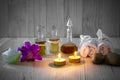 Bottles of aromatic oils with candles, pink orchid, stones and white towel on vintage wooden background with vignette Royalty Free Stock Photo