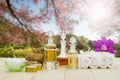 Bottles of aromatic oils with candles, pink orchid, stones and white towel on vintage wooden floor on lake and forest background