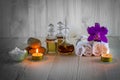 Bottles of aromatic oils with candles, pink orchid, stones and white towel on wooden background with vignette Royalty Free Stock Photo