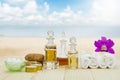 Bottles of aromatic oils with candles, pink orchid, stones and white towel on wooden floor on blurred beach and sky background Royalty Free Stock Photo