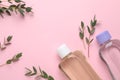 Bottles of baby oils and green leaves on pink background, flat lay. Space for text Royalty Free Stock Photo