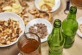 Bottles of beer and a mug next to a variety of snacks