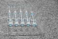 Bottles with blue liquid on a stand on a gray background. Vaccination, protection against viruses and air pollution