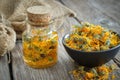 Bottles of calendula infusion, healthy marigold flowers in bowl and canvas sack on background. Herbal medicine Royalty Free Stock Photo