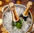 Bottles of champagne in bucket with ice on blurred background, closeup Royalty Free Stock Photo