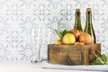 Bottles with cider, glasses and red apples in a wooden box on a kitchen table Royalty Free Stock Photo