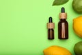 Bottles of citrus essential oil and fresh fruits on green background, flat lay. Space for text Royalty Free Stock Photo