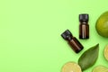 Bottles of citrus essential oil and fresh limes on green background, flat lay. Space for text Royalty Free Stock Photo