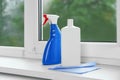 Bottles of cleaning products and dustrag on windowsill Royalty Free Stock Photo