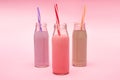 Bottles of colorful berry, strawberry and chocolate milkshakes with drinking straws