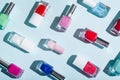 Bottles of colorful nail polish on pastel blue and pink background. Manicure and pedicure concept.