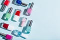 Bottles of colorful nail polish on pastel blue and pink background. Manicure and pedicure concept. Flat lay, top view, copy space