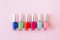 Bottles of colorful nail polish on pastel pink background. Manicure and pedicure concept. Flat lay, top view, copy space