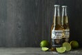 Bottles of Corona Extra and limes against dark wooden background