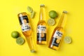 Bottles of Corona Extra, limes and salt on yellow background