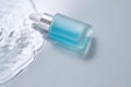 Bottles of cosmetics with a dropper in water on a blue background.