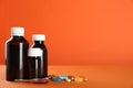 Bottles of cough syrup, dosing spoon and pills on orange background. Space for text Royalty Free Stock Photo