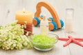 Bottles with cream for face skin and aromatic oil, bowl with sea salt, burning candle, starfish, hand massager and bouquet of