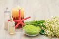 Bottles with cream for face skin and aromatic oil, bowl with sea salt, burning candle, starfish, hand massager and bouquet of