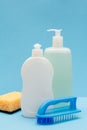 Bottles of dishwashing liquid, sponge and brush on blue background Royalty Free Stock Photo