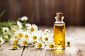 Bottles of essential oil for aromatherapy, alternative medicine or perfumery and a bouquet of fresh chamomile flowers on