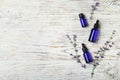 Bottles of essential oil and flowers on white wooden background, flat lay. Space for text Royalty Free Stock Photo