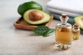 Bottles of essential oil, fresh avocado and towels on light wooden table, space for text Royalty Free Stock Photo