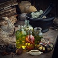 Bottles of essential oil or potion, mortar of dried moss, old books, dry roots and plants on old wooden table.