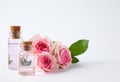 Bottles of essential oil and roses on white Royalty Free Stock Photo