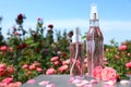 Bottles of facial toner with essential oil and fresh roses on table against blurred background.