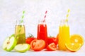 Bottles with fresh orange, apple, tomato juice and colored tubules on a gray concrete table. Royalty Free Stock Photo