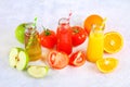 Bottles with fresh orange, apple, tomato juice and colored tubules on a gray concrete table. Royalty Free Stock Photo