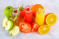 Bottles with fresh orange, apple, tomato juice and colored tubules on a gray concrete table. Royalty Free Stock Photo